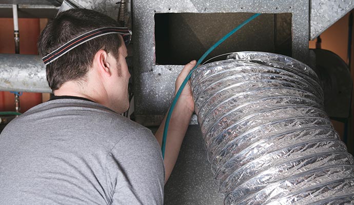 Technician inspecting and cleaning an HVAC duct system Technician inspecting and cleaning an HVAC duct system for maintenance