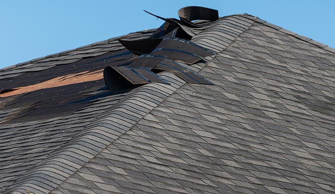 Close-up view of a damaged roof with missing shingles